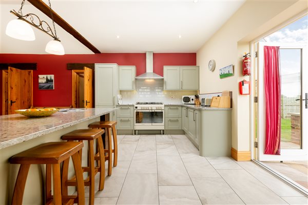 Pale green kitchen with range oven and large granite island